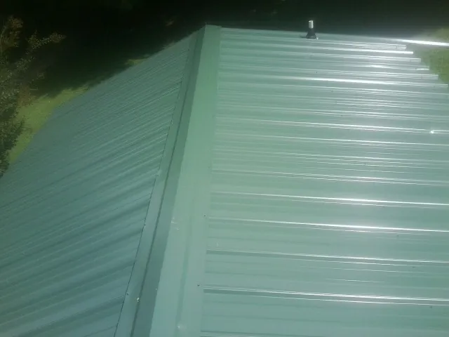 New green metal panels meeting at the ridge of a roof — Flat Roof Repair work by our crew in Punxsutawney