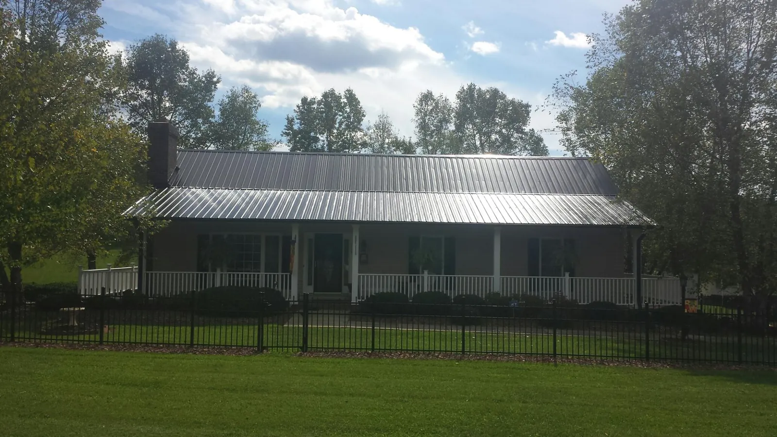 Gray metal roof on a brick ranch with a full width front porch — Gutter Guard Installation work by our crew in Punxsutawney