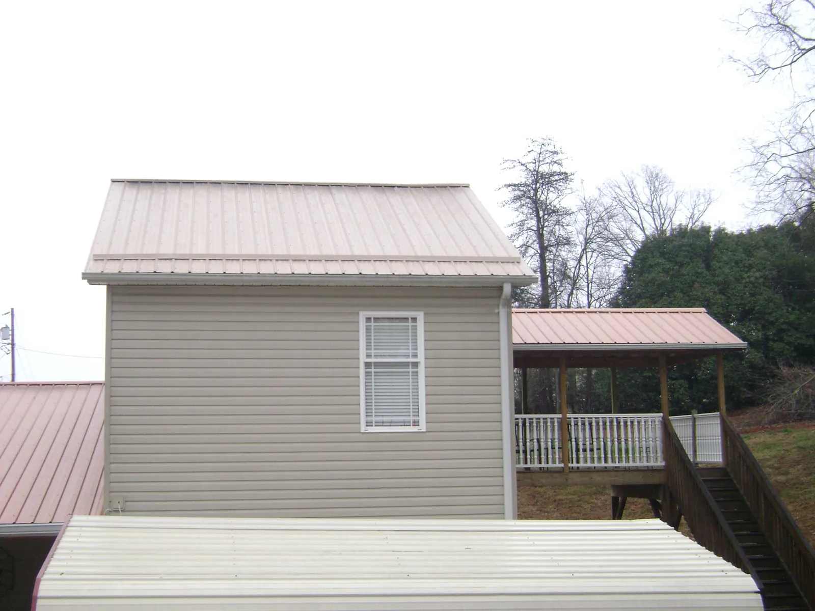 Tan metal roofs on a two story addition and attached porch, from a Roof Replacement job in Punxsutawney