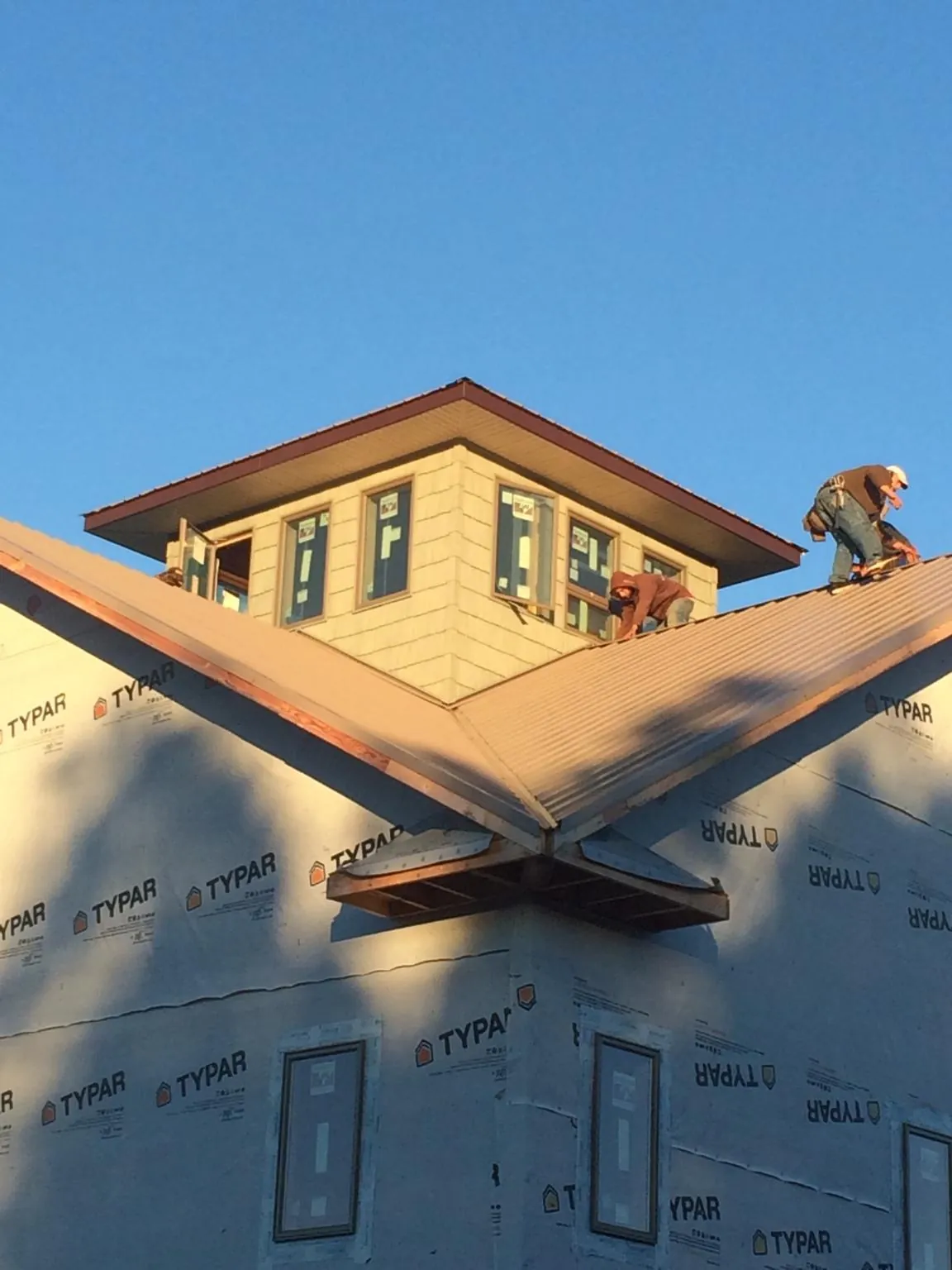 Roofers working around a rooftop cupola on a new metal roof at sunset — Roof Waterproofing in Punxsutawney by Roofing Brothers